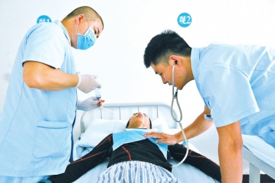 一名护士给病人喂食，另一名监测病人的身体状况。