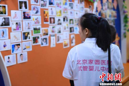 图为当日一名母亲正在观看墙上的“试管宝宝”照片?！⌒煺谆?摄