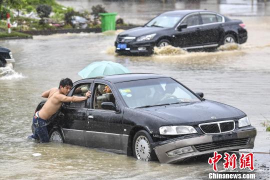 6月13日，惠州惠东县新平大道上，市民在雨中推行抛锚的车辆?！〕骆鲿F 摄