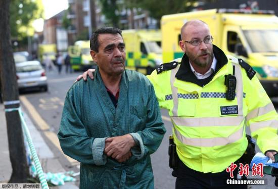 当地时间6月14日凌晨，伦敦西部一栋20余层的公寓大楼发生大火，火势猛烈，几乎蔓延到了所有楼层。约200名消防员和40辆消防车前往灭火。图为警方协助被疏散民众（左）撤离。