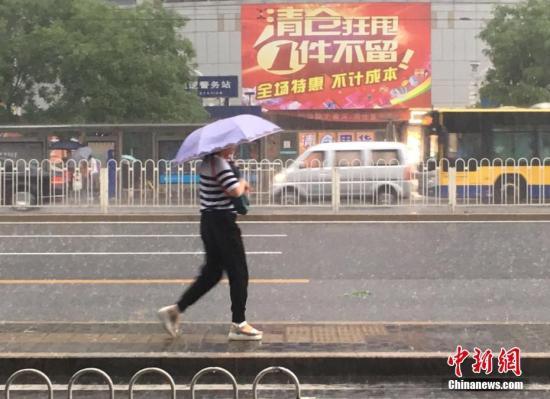 6月23日清晨，北京市民冒雨出行。 中新网记者 富宇 摄