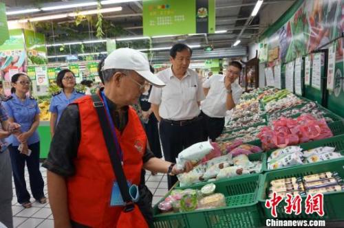 图为食品安全义工队员在超市对食品的生产日期进行检查 问泽英 摄 点击进入下一页