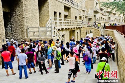 资料图：敦煌莫高窟窟区“游人如潮”。王斌银 摄