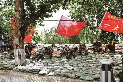 参与加固大堤的武警官兵在沙袋上休息 点击进入下一页