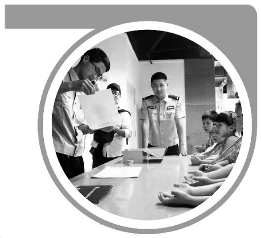 图2为2017年5月20日“彩虹亲子营”活动，湖北警察史博物馆讲解员刘泽恩（左一）为小朋友们讲解指纹按捺。