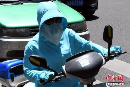 7月10日，福建省福州市民出行“全副武装”抵挡酷暑。刘可耕 摄