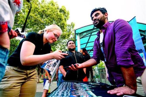 图为HanNation的团队成员塞舍尔(右)在校园里向留学生推介他们的APP。