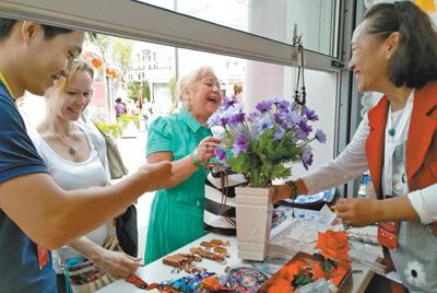 在莫斯科的北京地坛庙会上，北京民间工艺美术大师、绢花工艺传承人徐汶静(右一)带来的传统绢花颇受欢迎。本报记者 吴 焰摄