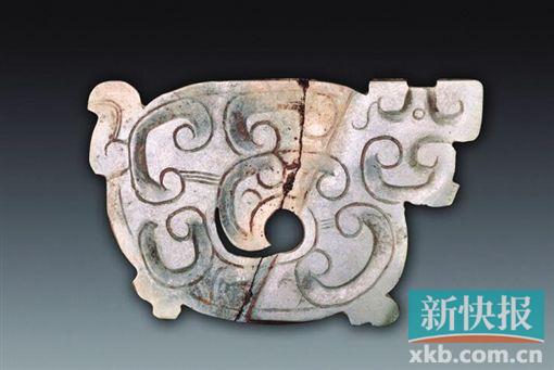 玉龙形饰 春秋 青绿色，薄片体。为长方形，身体卷曲，头侧视，圆形小眼，吻部前伸，下部似有双足，另一侧有一弯尾。一面饰勾云纹，中部身躯镂空成涡形孔，器物表面有切割痕。另一面光素无纹。春秋时期琢玉技艺有了很大的进步，制出了更为精美的玉器，纹饰从平面向隐起、从简单到繁复的方向发展，雕刻技法采用浮雕、镂空与阴刻相结合。