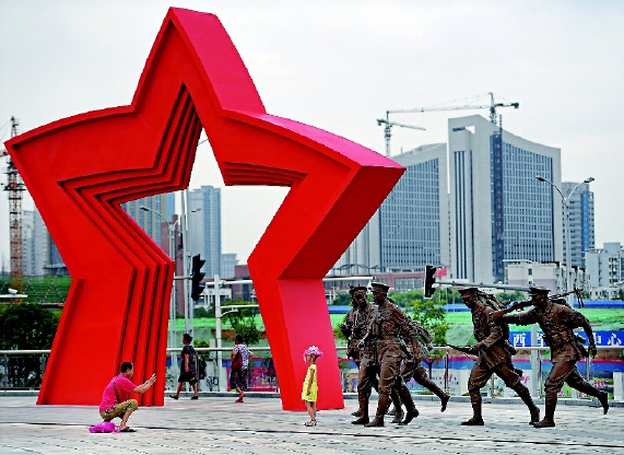 南昌，人民军队诞生的地方。在这座有着“英雄城”美誉的城市街头，以“八一”命名的地方随处可见：八一广场、八一公园、八一大道、八一起义纪念碑……这一切，都源于90年前8月1日发生在这里的一次影响深远的武装起义。八一南昌起义，让南昌这个军旗升起的地方烙上了深深的红色印记。图为在南昌建军雕塑广场，一位家长在给孩子拍照。    新华社发