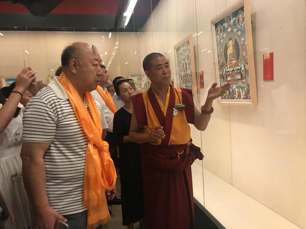 中国工艺美术大师和国家级非物质文化遗产代表性传承人更登达吉（右）向来宾介绍展品。