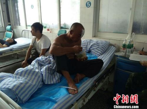 获救渔民丁兆兰光着上身，左额头用纱布包着，正在吃着医务人员送来的午饭。于从文 摄