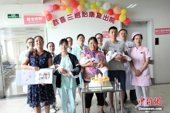 图为医护人员和三胞胎及家人合影。 钟欣 摄