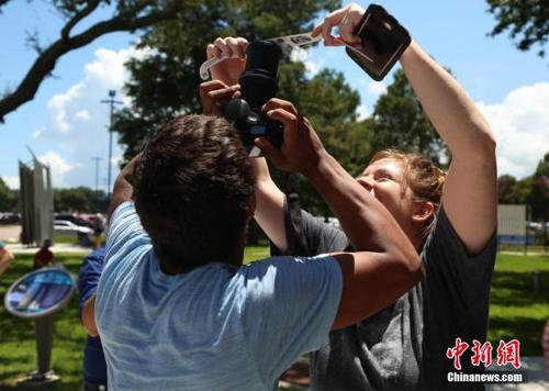 当地时间8月21日，美国迎来罕见日食景观。图为休斯敦太空中心独立广场上，游客将日食眼镜挡在镜头前拍摄日食景观。 <a target='_blank' href='http://www.chinanews.com/'>中新社</a>记者 曾静宁 摄