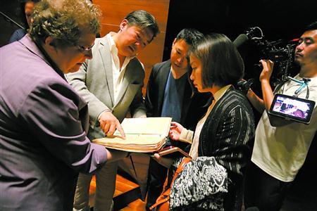 中国侨网克里斯缇娜（左一）介绍纪念册内容。 蔡磊磊　摄