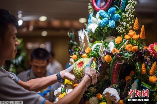 资料图：一名泰国男子用雕刻的水果和蔬菜拼成一件精心制作的装饰品。