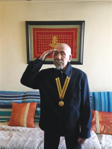 去年初，关爱抗战老兵组织为董老颁发纪念章，他起身敬礼致谢。图片来源：新京报