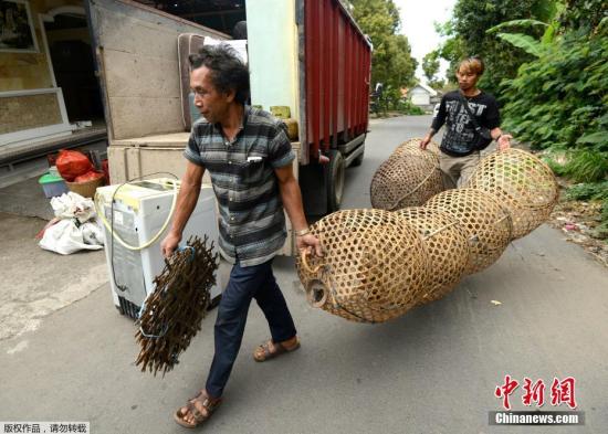 当地时间9月21日，印尼巴厘岛阿贡火山周围地壳运动大幅度加强，印尼地质局已将其警戒级别提升至第三级，该警戒级别表示火山两星期内存在喷发的可能性。图为当地居民携带物品离开危险区域。