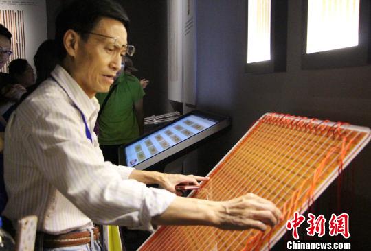 图为参展观众在现场体验古代算表的计算方式。　赵晓 摄