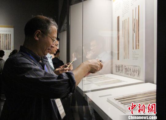 图为参展观众在中国简帛文化展上观看和拍摄简帛文物?！≌韵∩? longdesc=
