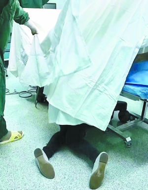 ▲事发当晚，王媚半跪在病床床尾一角，右手一直托举着产妇腹中的胎儿。