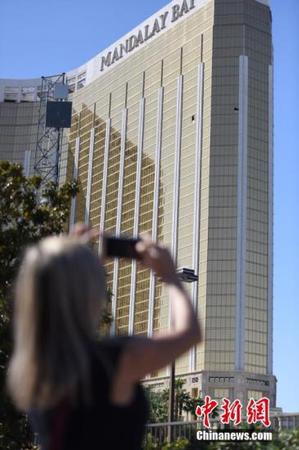 当地时间10月4日上午，美国拉斯维加斯曼德勒海湾酒店门前道路解除封锁、恢复行人和车辆通行，只是在酒店正门口仍有黄色警戒线、警车和全副武装的警察。金碧辉煌的酒店外墙上，两个黑洞洞的破损窗口触目惊心。10月1日晚，一名枪手正是砸破了这两处窗户，向不远处举行露天乡村音乐节的人群扫射，夺去50多人生命，造成美国现代历史上伤亡最惨重的枪击事件。很多当地民众和外国游客4日来到这里，举着手机拍下这两个“夺命窗口”。 <a target='_blank' href='http://www.chinanews.com/'>中新社</a>记者 张朔 摄