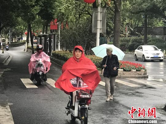 11日，南京迎来降温降雨。图为市民披上雨衣出行?！⊙钛沾?摄