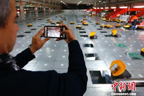 图为在申通物流公司内，记者在拍摄智能机器人自动分检系统的工作实况?！「惶?摄