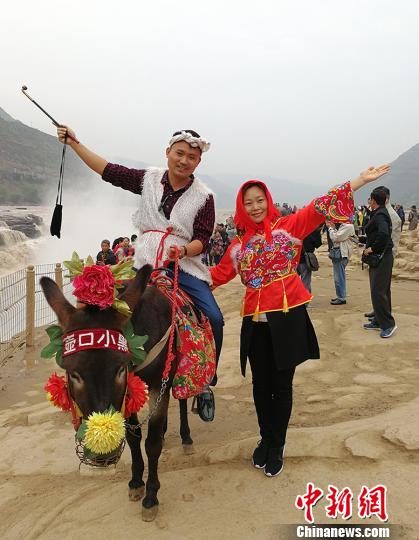 缅甸南坎明德学校的负责人杨蜜蜜与弟弟杨彪在黄河岸边穿上极具地方特色的服饰，骑着毛驴合影留念?！⊙罱苡?摄