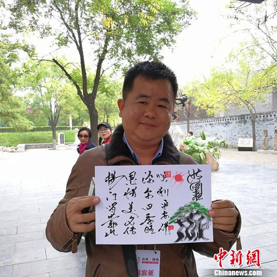 缅甸大其力大华学校负责人杨恩源在洪洞大槐树景区向记者展示自己姓氏的文创产品?！⊙罱苡?摄