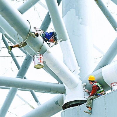 粗壮的钢结构犹如大树的主干和次干，枝繁叶茂，富有活力。工人师傅们正在滚涂防火涂料。