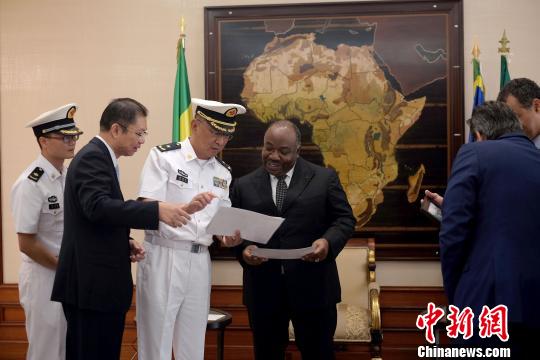 当地时间10月5日，在加蓬总统府，“和谐使命—2017”任务指挥员管柏林向加蓬总统邦戈赠送2009年中加“和平天使”联合演习中邦戈总统的资料照片。　江山 摄