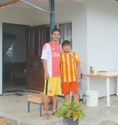 塔诺阿莱客索诺·阿莱克斯和儿子在新房前合影。 　　本报记者 颜 欢摄