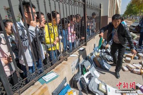 10月8日，山西太原，山西财经大学校园外一处空地上摆满各个物流公司发来的快递，众多学生隔着栅栏排队等候收取。国庆节后高?？兹沼次锪鞲叻?，积压一周的学生网购物品集中分发，现场一片忙碌。武俊杰 摄