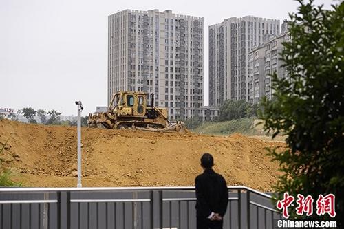 资料图：市民观望一楼盘工地上的推土机作业。<a target='_blank' href='http://www.chinanews.com/'>中新社</a>记者 杨华峰 摄