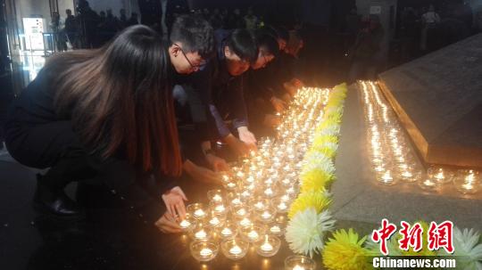 12月13日，沈阳“九一八”历史博物馆在国家公祭日举行悼念仪式。图为民众向寓意民族英烈浩气长存的金字塔型卧碑敬献烛火。　朱明宇 摄