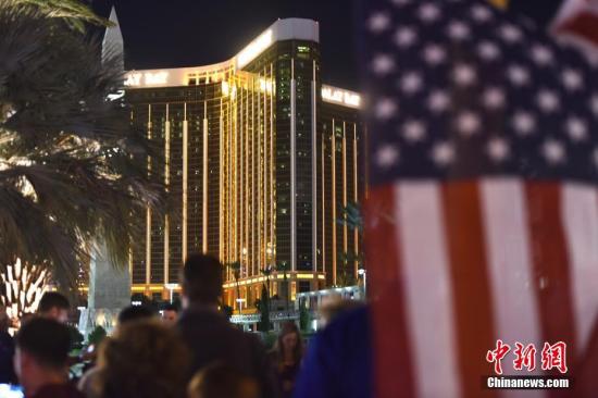 当地时间10月3日晚，很多人聚集在美国拉斯维加斯市中心曼德勒海湾酒店附近，悬挂起一面美国国旗，用烛光和鲜花吊唁10月1日晚那场严重枪击事件中的遇难者。 <a target='_blank' href='http://www.chinanews.com/'>中新社</a>记者 张朔 摄