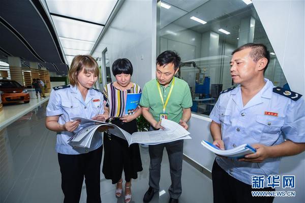 浙江省长兴县地税局工作人员在新能源企业超威集团给相应部门工作人员（左二、左三）介绍最新的税收优惠政策（2017年7月14日摄）。8