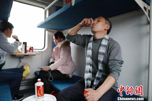 48岁的张师傅喝着朋友送的酒，和儿子和儿媳妇一起回云南昭通老家过年?！∫罅⑶?摄