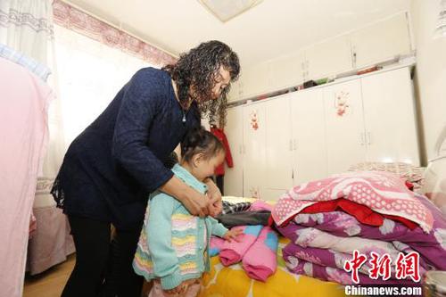 图为彭秀芳妈妈为玲玲穿新衣?！『罅?摄