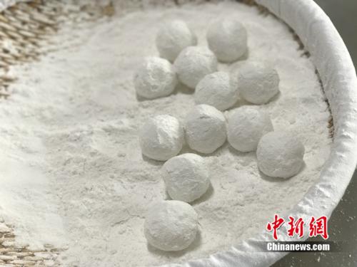 "制作元宵时，首先要将馅料做好，沾上水，再投进盛满糯米粉的笸箩内摇。<a