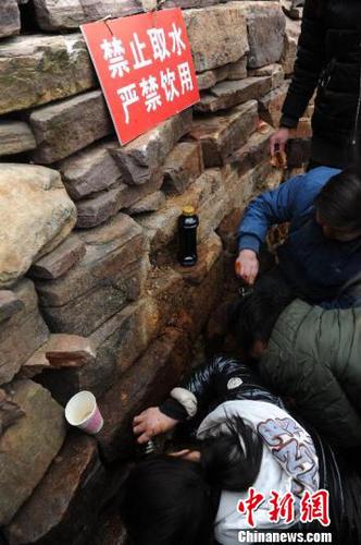 当地政府部门在渗漏不明液体的石崖处，设置明显标识，提醒群众不可饮用。　孟梅 摄