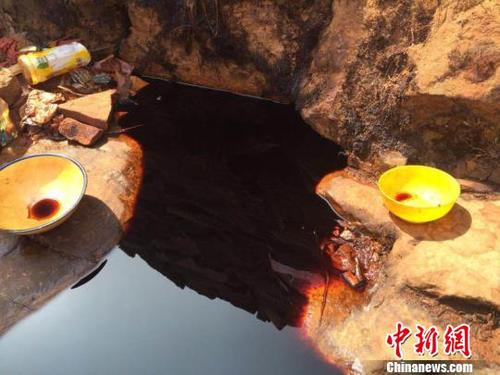 从石崖缝隙里渗出的黑褐色不明液体，从颜色看如酱油状。　刘鹏 摄