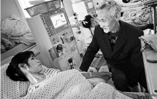 吴水根在病榻前照顾做透析的秦霞仙。 点击进入下一页