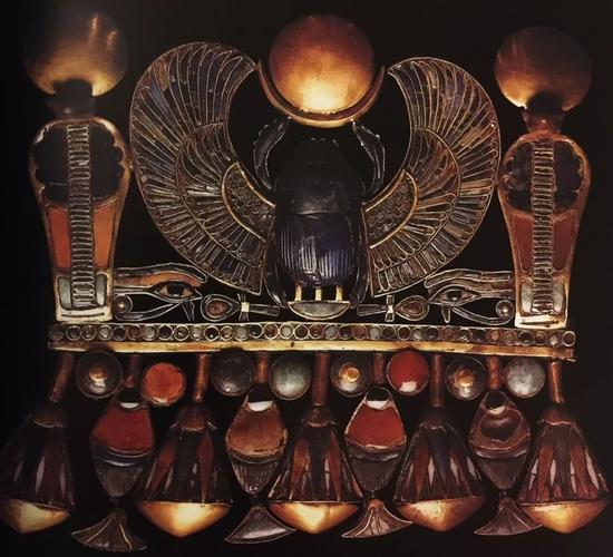 法老图坦卡蒙的胸饰 　　图案主题包括：展翅圣甲虫、上下埃及王之名、生命之符、荷鲁斯之眼以及莲花和纸莎草边饰 　　古埃及第十八王朝，约公元前1323年