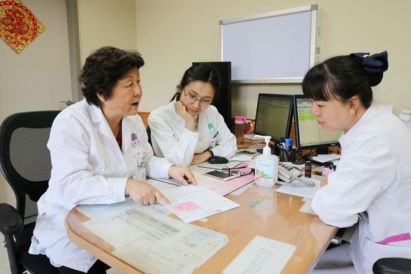 廖秦平在门诊中和医生一起讨论病例。杨欣 摄