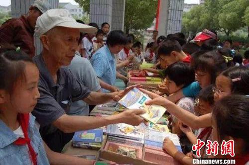 周火生和志愿者们通过书籍义卖筹集捐助款。周火生希望爱心接力可以不断延续下去。　资料图片 摄