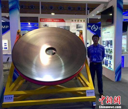 张舸博士和展出的碳化硅反射镜。中科院长春光机所供图