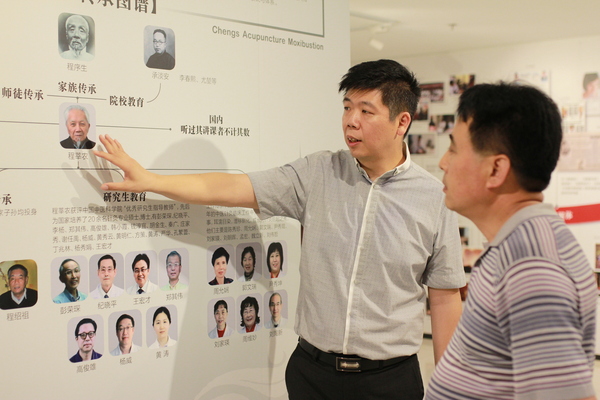 程凯（左）为参观展览的领导、专家介绍程莘农院士学术思想传承体系