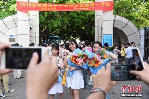 资料图：2018年高考结束，家长为刚刚走出考场的孩子拍照留念。 王以照 摄 